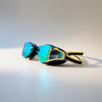 luwa Apex Elite black and gold swim goggles with blue mirrored lenses and adjustable strap.