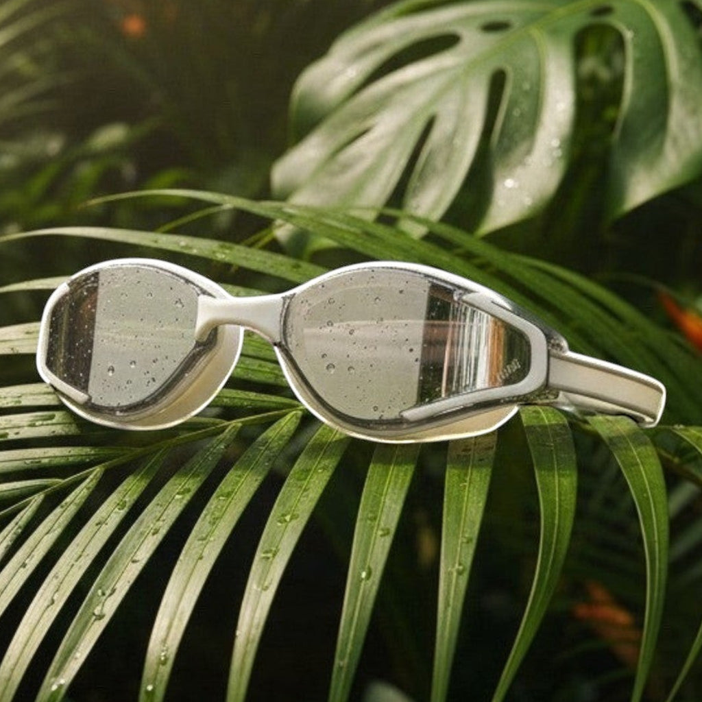 LUWA Apex Elite white and silver sport goggles with anti-fog coating and UV protection, resting on a palm leaf.